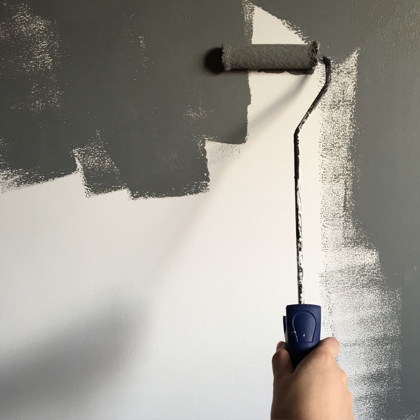 Photo d’illustration : application de peinture grise au rouleau sur un mur.